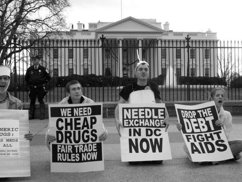 Protesters on World AIDS Day holding signs that say "Cheap Drugs" and "Needle Exchange in DC NOW"